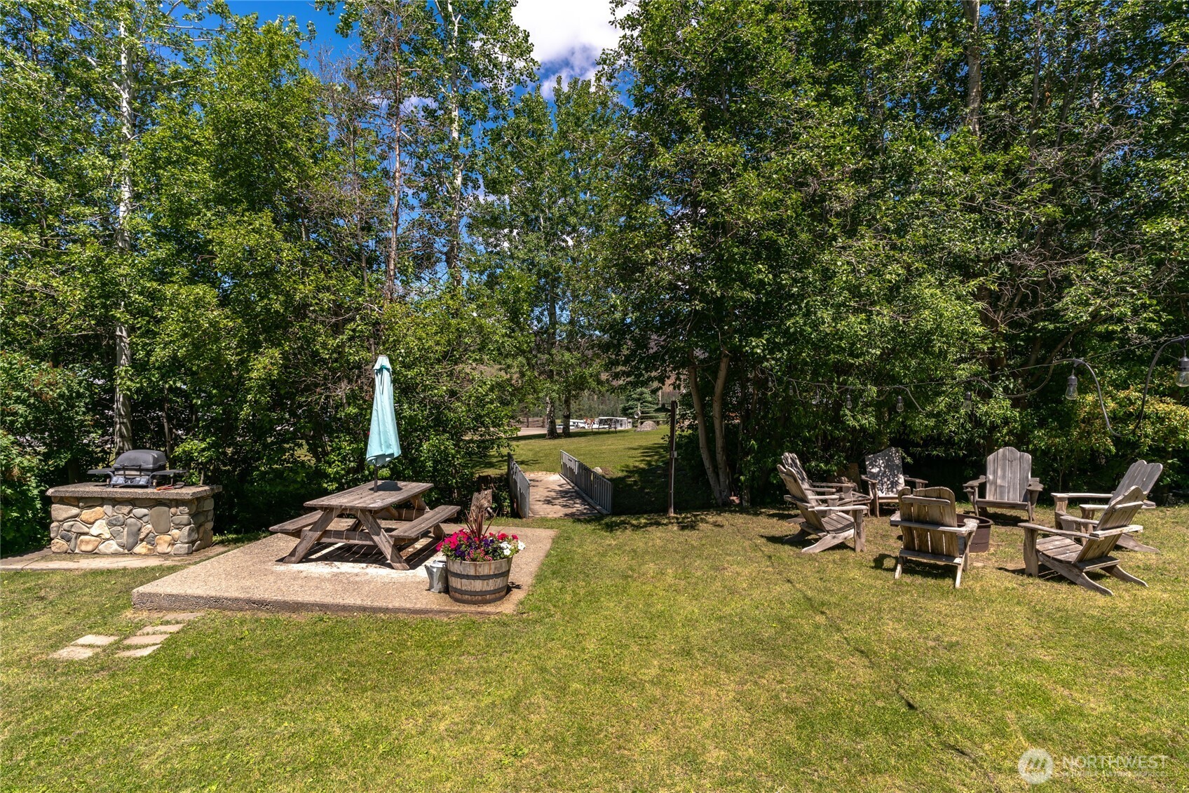 579 Eastside Chewuch Road Winthrop, WA 98862 - Photo 14 of 37 a view of a patio with table and chairs and potted plants with large trees