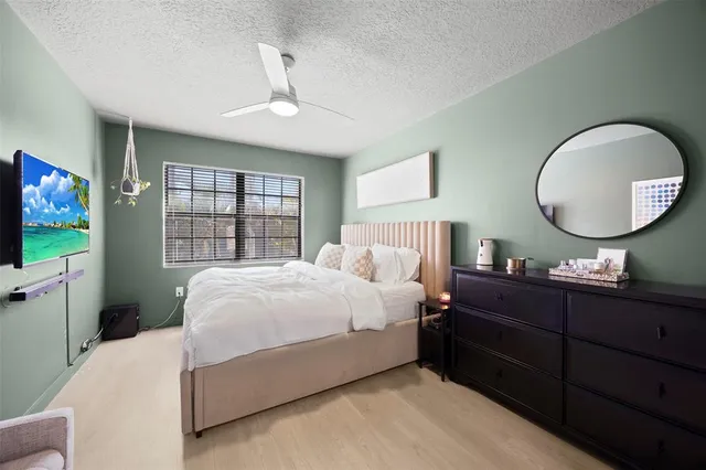 a bedroom with a large bed and a flat tv screen on dresser