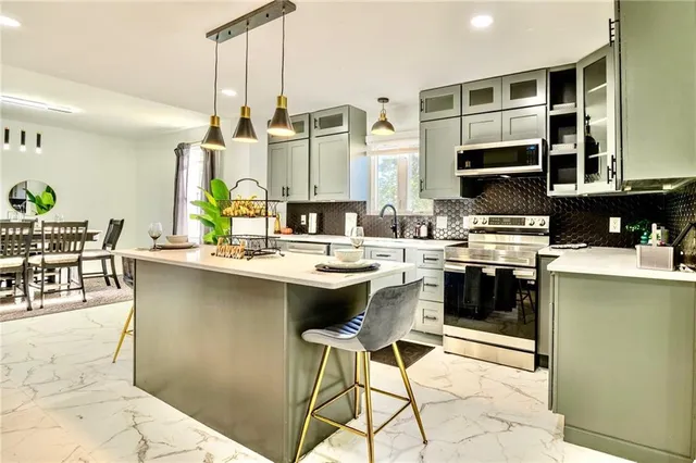 a kitchen with stainless steel appliances kitchen island granite countertop a stove a sink and a microwave