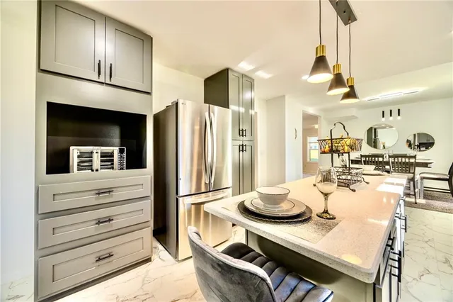 a kitchen with stainless steel appliances kitchen island granite countertop a refrigerator and cabinets