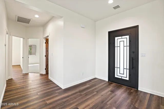 a view of a hallway with wooden floor and a bathroom