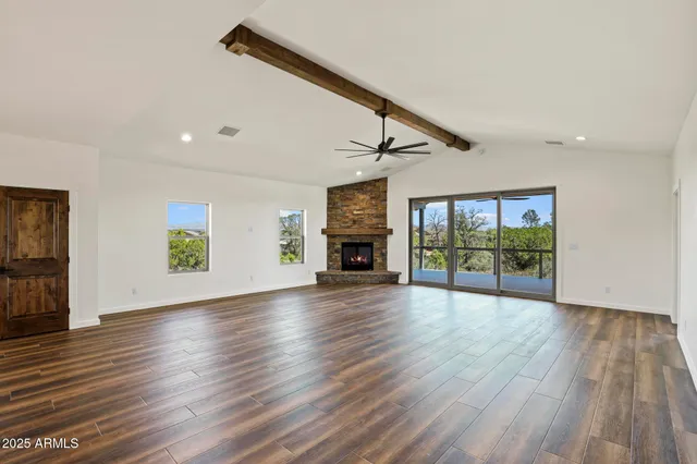 a view of an empty room with wooden floor fireplace and windows