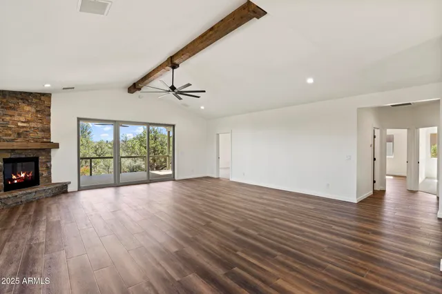 an empty room with wooden floor fireplace and windows