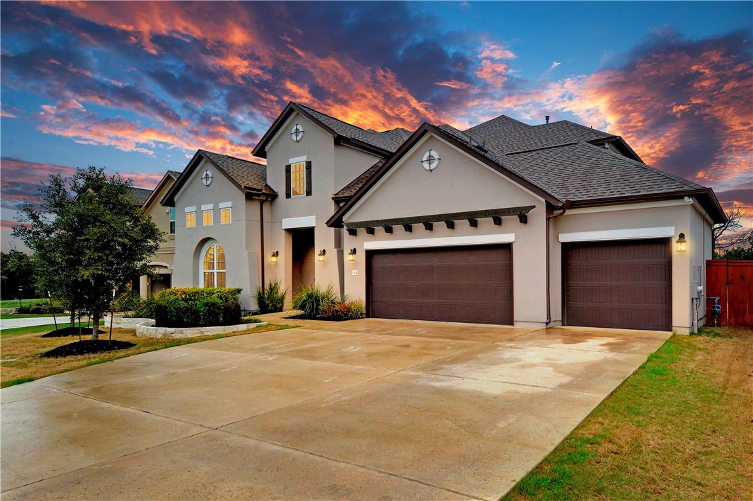 a view of yellow house with large trees and a yard in front of it