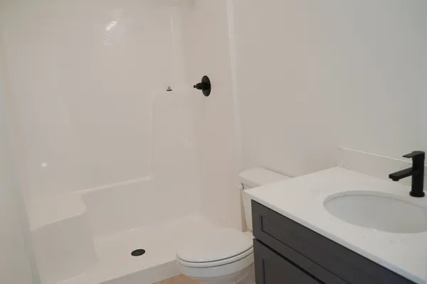 a bathroom with a granite countertop sink a toilet and shower