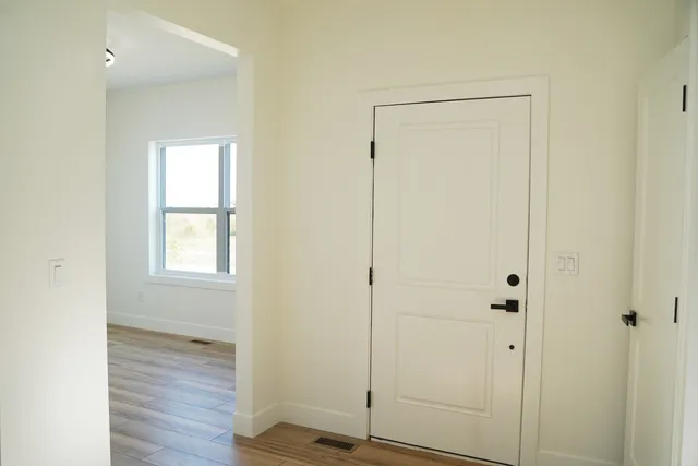 a view of an empty room with wooden floor and closet