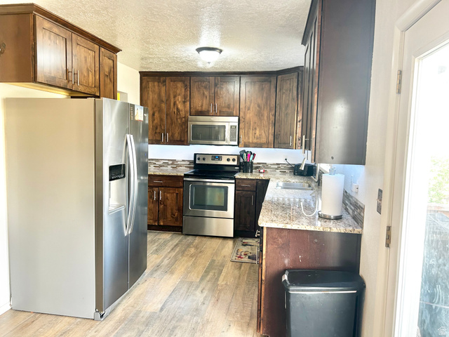 570 250 East Parowan, UT 84761 - Photo 5 of 27 Kitchen featuring wood-finish cabinetry, stainless steel appliances, speckled stone countertops, and a patterned tile backsplash