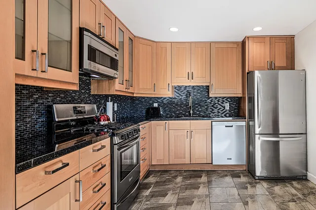 a kitchen with stainless steel appliances granite countertop a refrigerator and a stove top oven