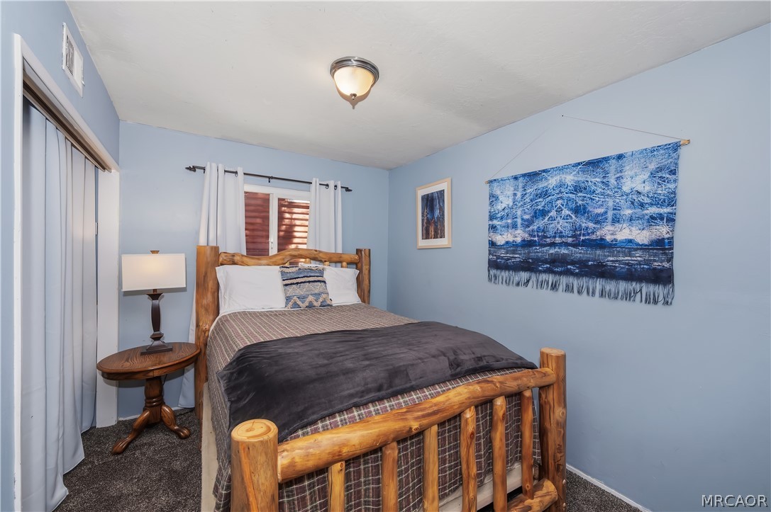 1099 Canyon Road Fawnskin, CA 92333 - Photo 18 of 39 a bedroom with a bed a lamp and a window