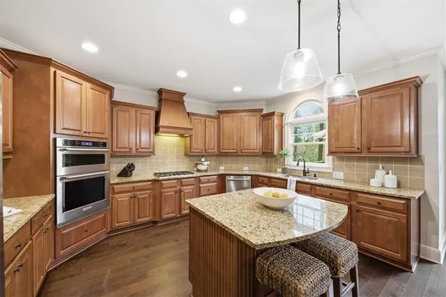a kitchen with stainless steel appliances granite countertop a kitchen island a refrigerator a sink a stove and island