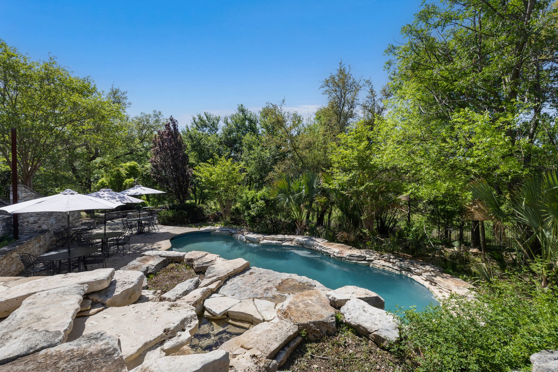 18059 Ranch To Market Road 1826 Buda, TX 78610 - Photo 20 of 39 Swimming pool with outdoor dining space, a patio, a small pond, and view of wooded area