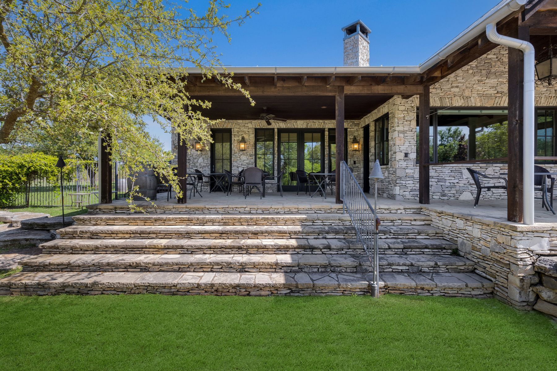 18059 Ranch To Market Road 1826 Buda, TX 78610 - Photo 23 of 39 Rear view of house with a patio area, stone siding, a chimney, and a ceiling fan