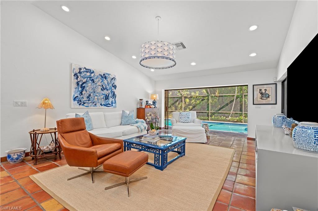 2419 Pinewoods Circle, Unit 11 Naples, FL 34105 - Photo 17 of 32 a living room with furniture a flat screen tv and a large window