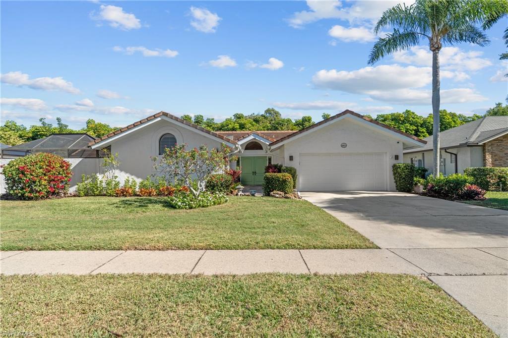 2419 Pinewoods Circle, Unit 11 Naples, FL 34105 - Photo 2 of 32 a front view of a house with a yard and garage