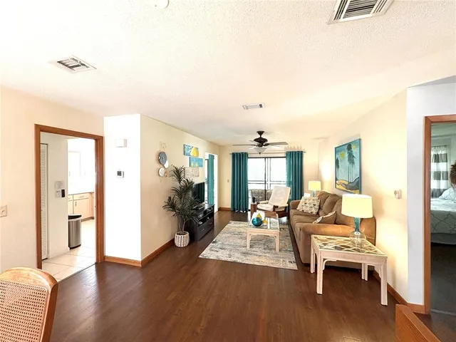 a living room with furniture a large window and wooden floor