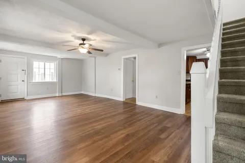 a view of an empty room with wooden floor and staircase