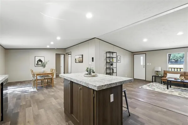a view of kitchen island a sink wooden floor and a dining table chair