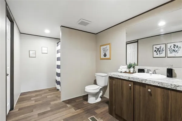 a bathroom with a granite countertop sink a toilet and a mirror