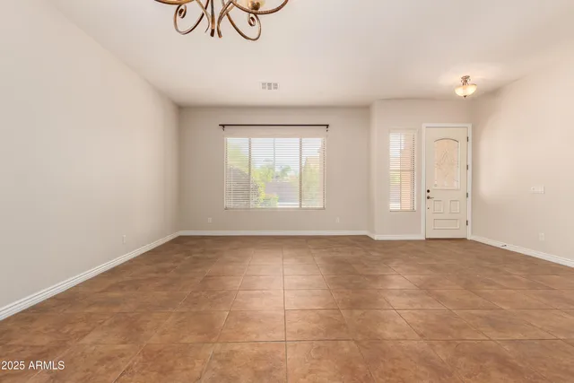 an empty room with a fireplace and chandelier fan