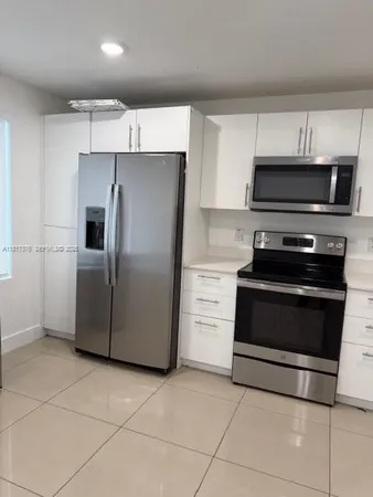 a kitchen with granite countertop a refrigerator and a stove top oven