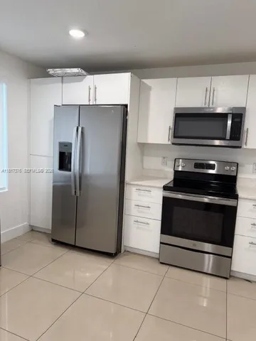 a kitchen with granite countertop a refrigerator and a stove top oven