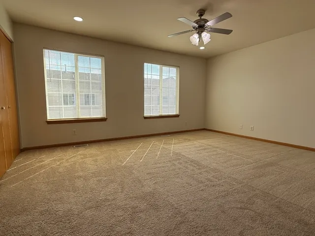 an empty room with windows and ceiling fan