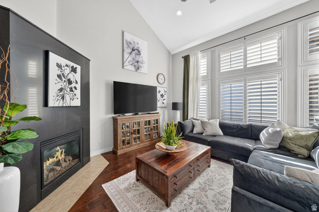 14738 Tangle Hill Road Herriman, UT 84096 - Photo 24 of 66 Living area featuring an integrated fireplace with a dark finish, tall vaulted ceilings, and a large window wall with white louvered shutters