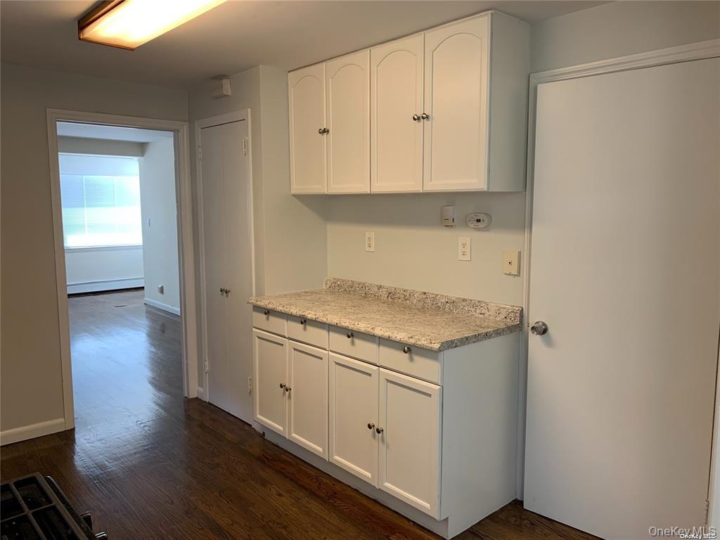 44 Graywood Road, Unit 2 Port Washington, NY 11050 - Photo 4 of 17 a kitchen with granite countertop white cabinets and a wooden floor
