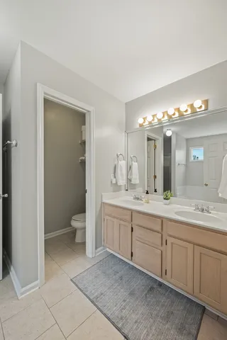 a spacious bathroom with a double vanity sink toilet and a mirror