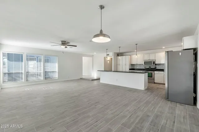 a large kitchen with stainless steel appliances kitchen island a large counter top and wooden floor