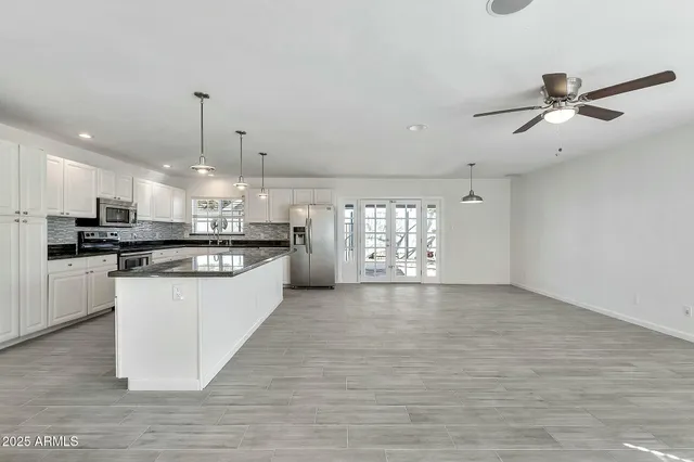 a view of kitchen and empty room with wooden floor