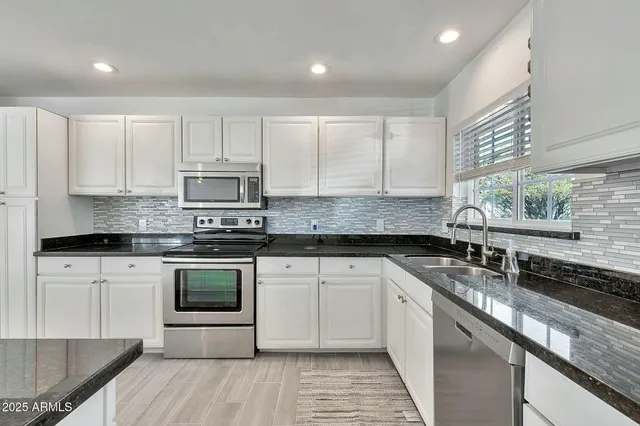 a large white kitchen with a refrigerator a sink and white cabinets