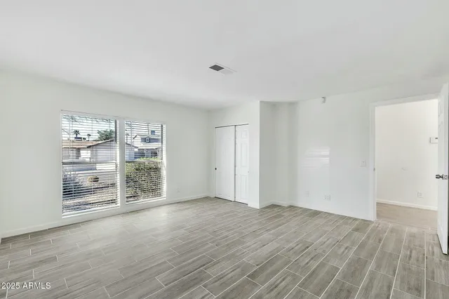 an empty room with wooden floor and windows