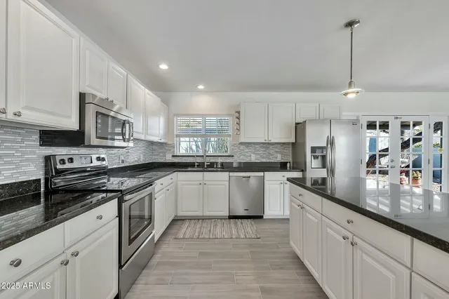 a kitchen with stainless steel appliances granite countertop a sink a stove and cabinets