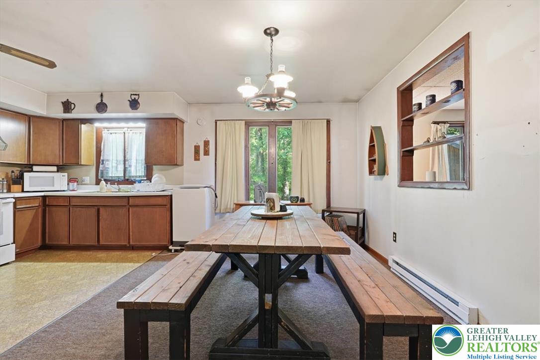 143 Logger Road Canadensis, PA 18325 - Photo 8 of 32 A combined kitchen and dining area features abundant wood cabinetry and a rustic picnic-style dining table.