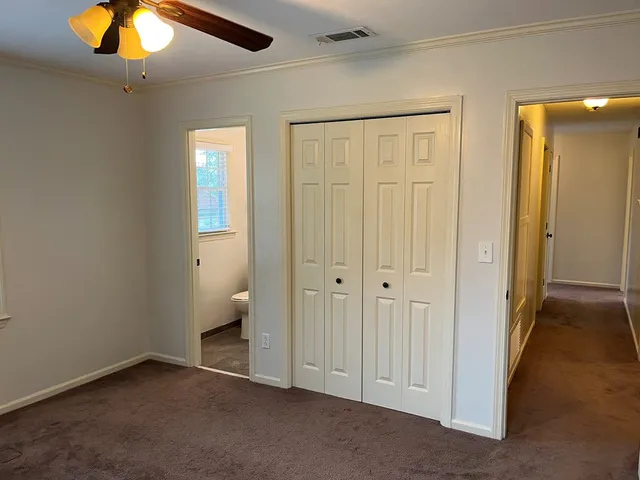 an empty room with closet and a chandelier fan