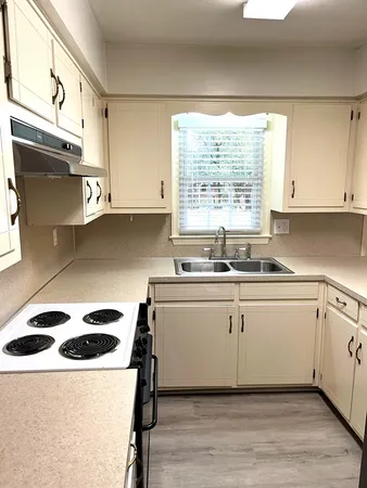 a kitchen with a white cabinets and wooden floor