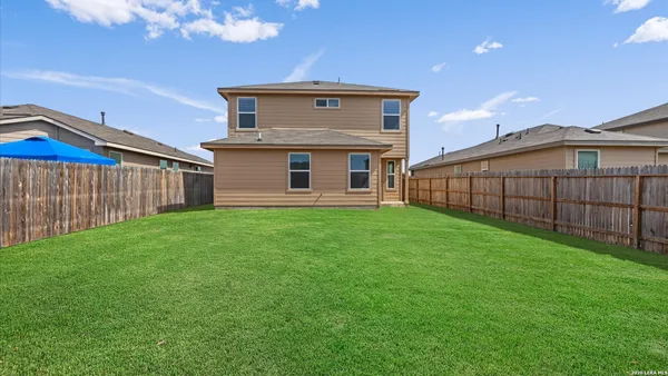 a view of a house with a yard and wooden fence