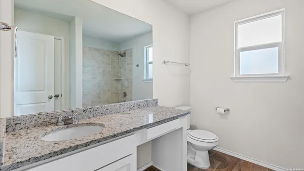 a bathroom with a granite countertop sink a toilet and a mirror