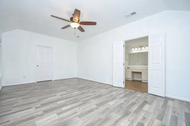 a view of an empty room with a ceiling fan window and a ceiling fan