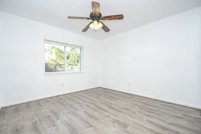 an empty room with wooden floor and chandelier fan