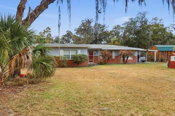 a front view of a house with a yard and tree