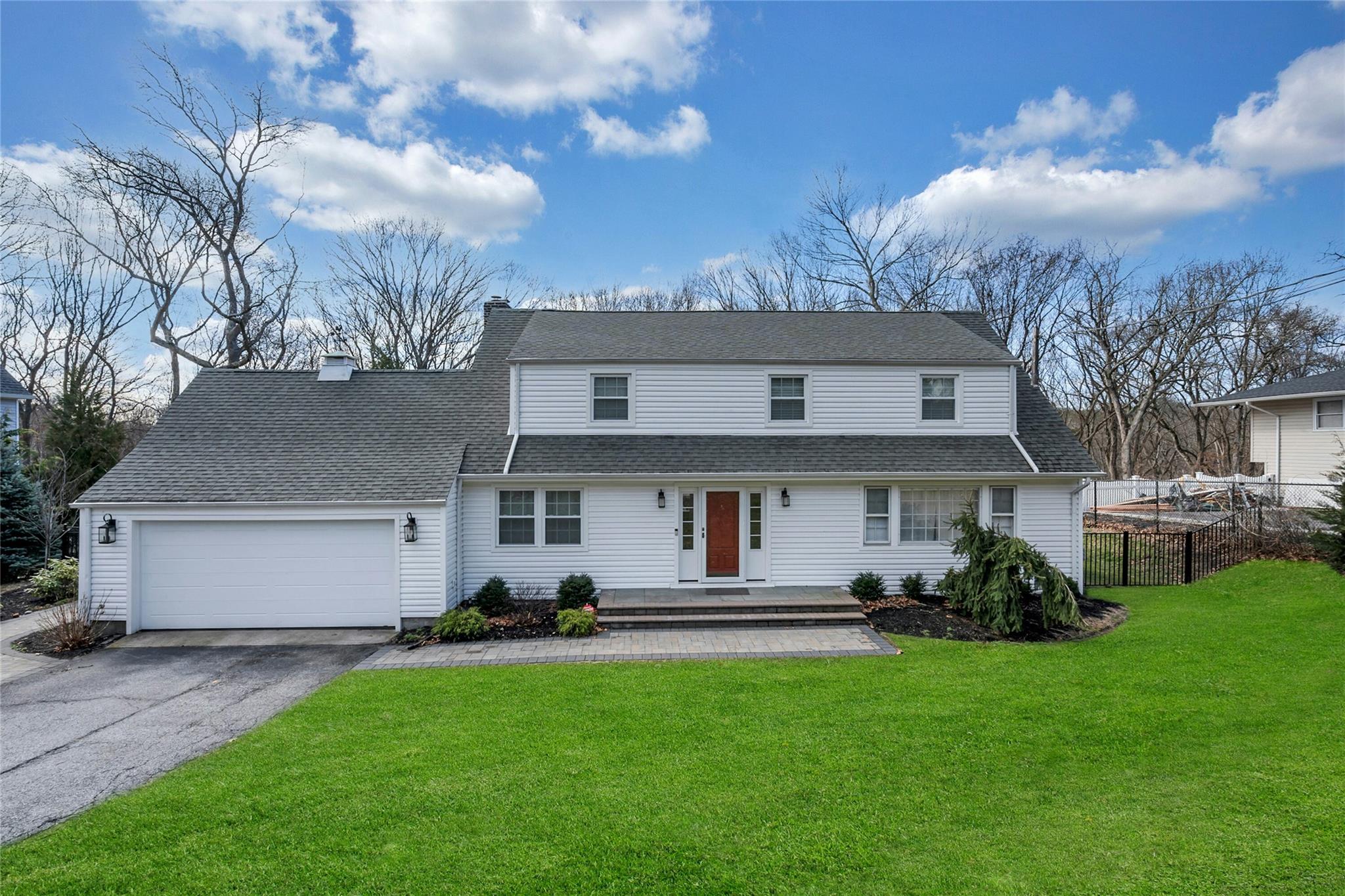 Traditional home featuring roof with shingles, fence, an attached garage, driveway, and a front lawn