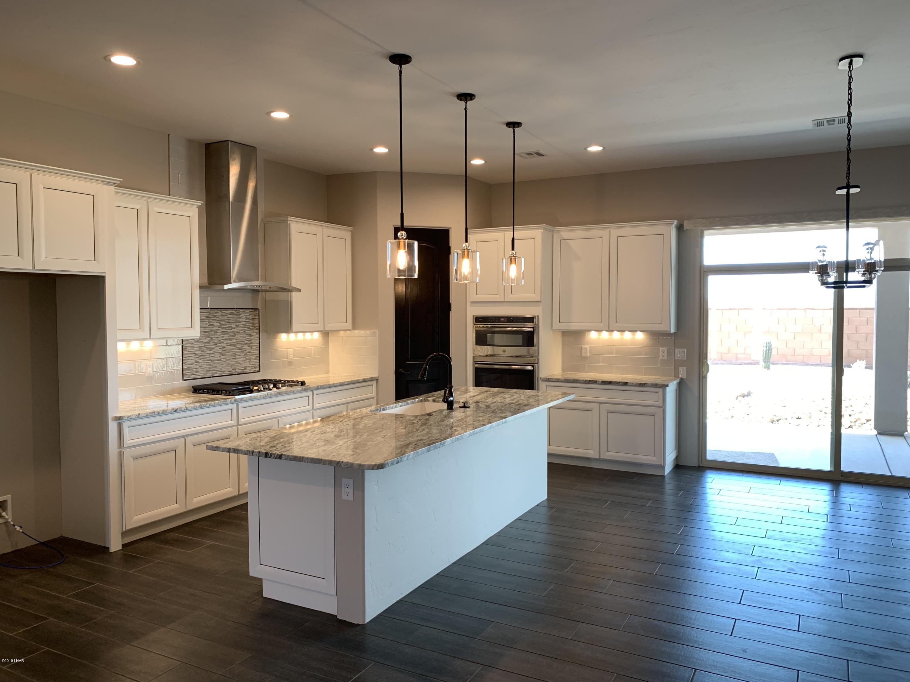 4731 North Juneberry Road Lake Havasu City, AZ 86404 - Photo 11 of 52 a large kitchen with stainless steel appliances a large counter top a stove a sink dishwasher and a refrigerator with wooden floor