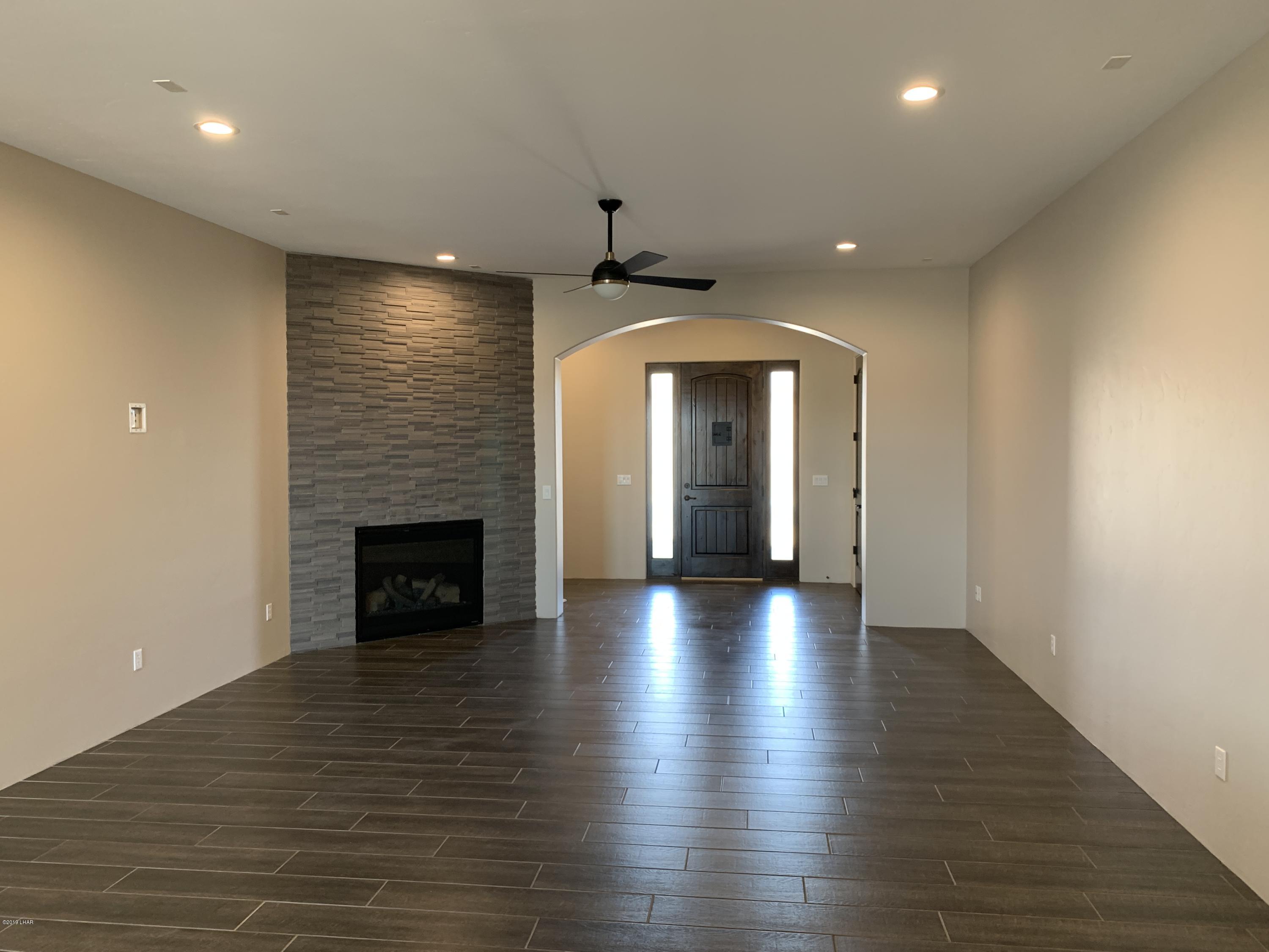 4731 North Juneberry Road Lake Havasu City, AZ 86404 - Photo 9 of 52 an empty room with wooden floor fireplace and windows