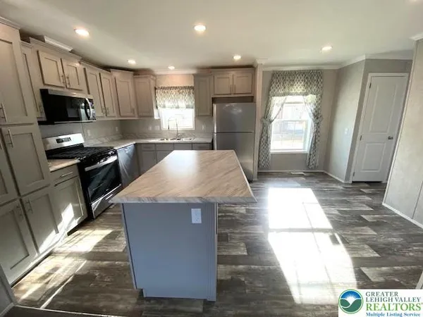 a kitchen with stainless steel appliances kitchen island granite countertop a stove a sink and a refrigerator