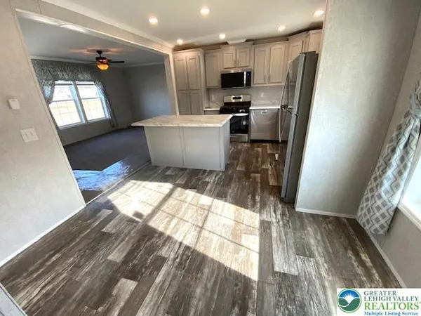 a kitchen with stainless steel appliances a refrigerator and a wooden floor