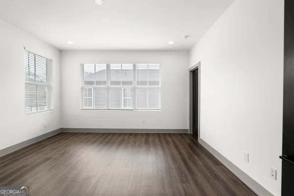 a view of an empty room with wooden floor and closet
