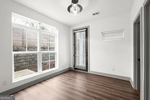 a view of an empty room with wooden floor and closet