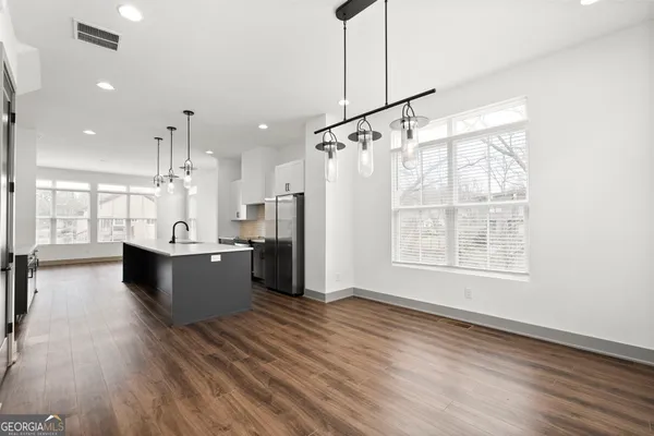 a living room with furniture and kitchen view with wooden floor